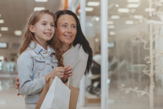 Nettes kleines Mädchen, das im Einkaufszentrum mit ihrer Mutter kauft