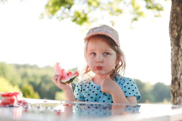Nettes kleines Mädchen, das im Sommer Wassermelone im Freien isst Kind und Wassermelone im Sommer