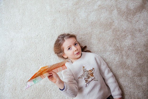 Nettes kleines Mädchen, das mit einem Papierflugzeug spielt