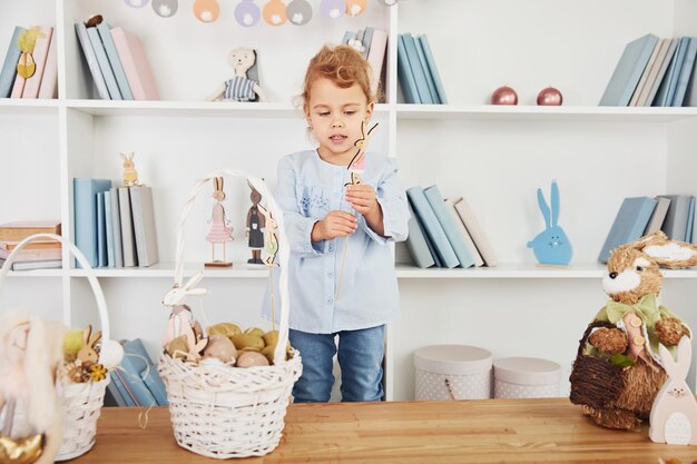 Nettes kleines Mädchen, das mit Spielzeug spielt, wenn es die Osterferien drinnen feiert