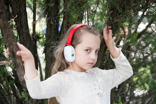 Nettes kleines Mädchen, das Musik mit Kopfhörern am Sommertag genießt