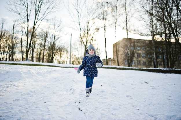 Nettes kleines Mädchen, das sich am Wintertag im Freien amüsiert.