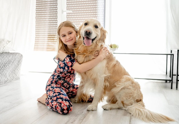 Nettes kleines Mädchen, das sich zu Hause mit einem wunderschönen Goden Retriever-Hund umarmt