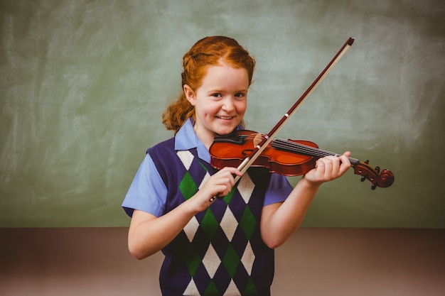 Nettes kleines Mädchen, das Violine im Klassenzimmer spielt