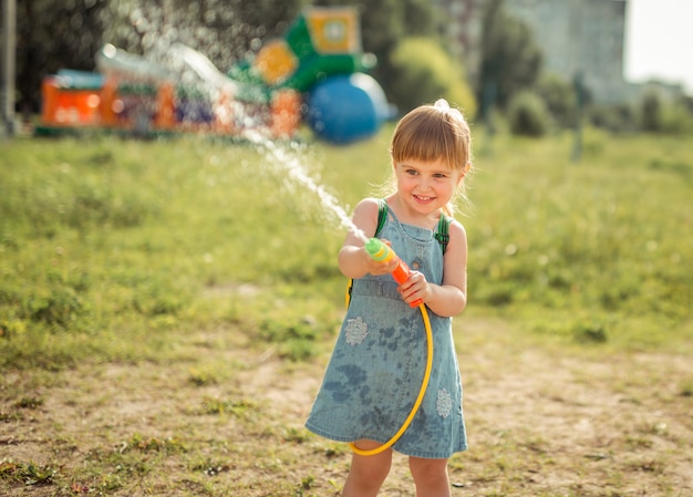 Nettes kleines Mädchen, das Wasserwerfer spielt