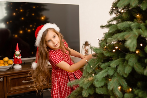 Nettes kleines Mädchen, das Weihnachtsbaum zu Hause verziert