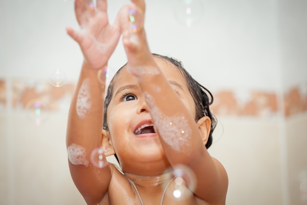 Nettes kleines Mädchen des Kindes, das mit Blase im Badezimmer badet und spielt