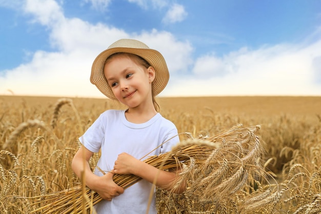 Nettes kleines Mädchen hält goldene Roggenohren beim Gehen auf Weizenfeld