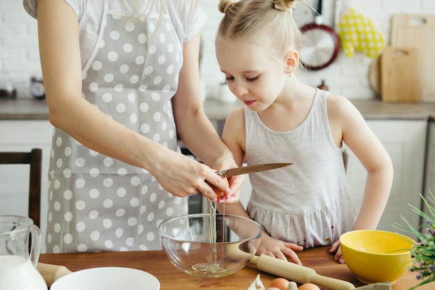 Nettes kleines Mädchen hilft Mama beim Backen von Keksen in der Küche. Glückliche Familie. Tonisieren.