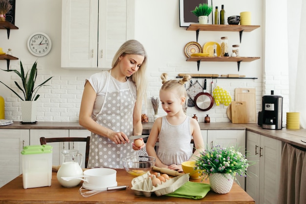 Nettes kleines Mädchen hilft Mama beim Backen von Keksen in der Küche. Glückliche Familie. Tonisieren.