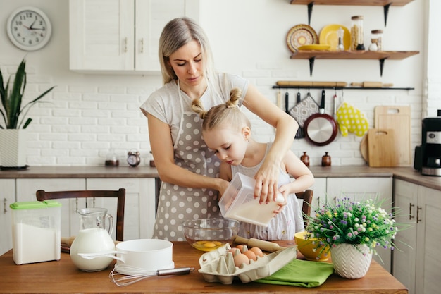 Nettes kleines Mädchen hilft Mama beim Backen von Keksen in der Küche. Glückliche Familie. Tonisieren.