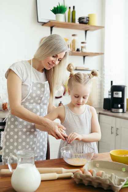 Nettes kleines Mädchen hilft Mama beim Backen von Keksen in der Küche. Glückliche Familie. Tonisieren.