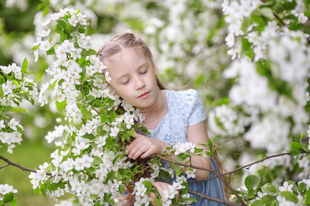 Nettes kleines Mädchen im blühenden Apfelbaumgarten im Frühjahr