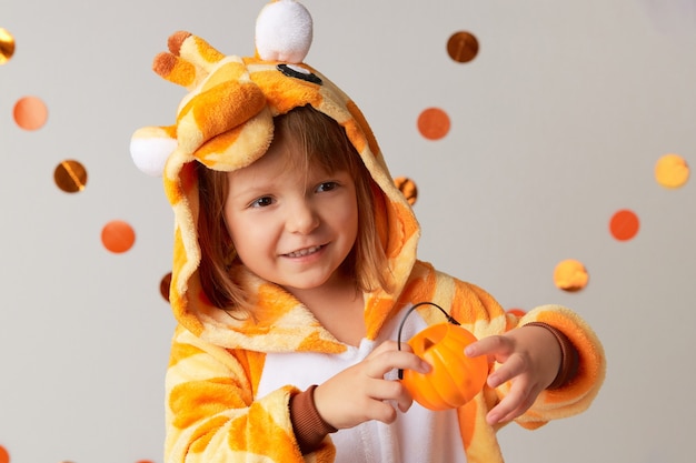 Nettes kleines Mädchen im Giraffenkostüm, das Kürbiskerzenhalter zu Hause Halloween-Party hält