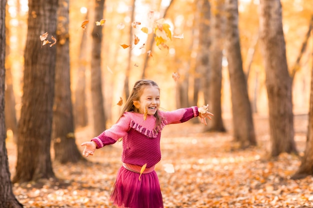 Nettes kleines Mädchen im Herbstpark mit orangefarbenen und gelben Farbblättern