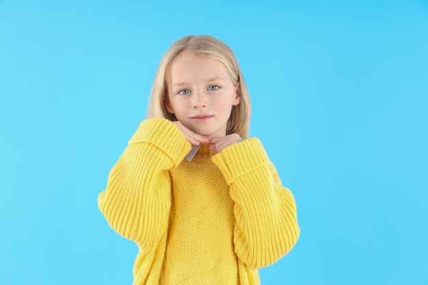 Nettes kleines Mädchen im Pullover auf blauem Hintergrund