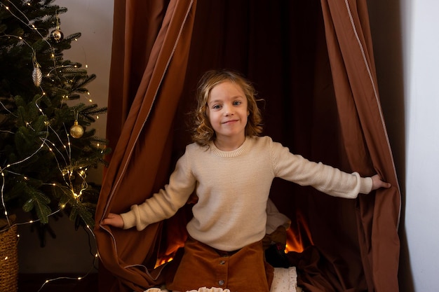 Foto nettes kleines mädchen im weihnachtshaus vor dem hintergrund des weihnachtsbaums