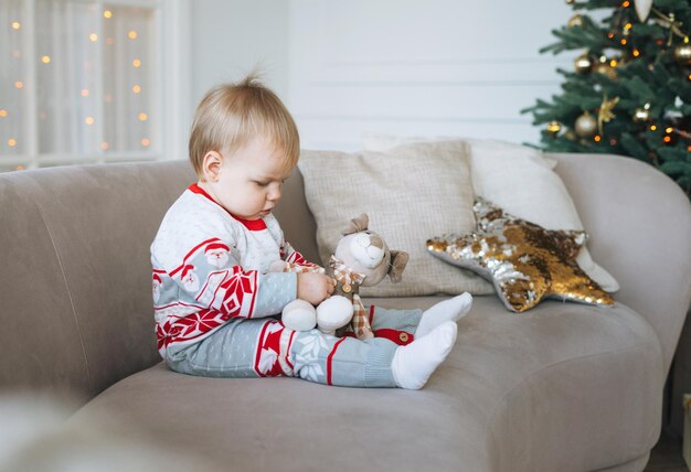 Nettes kleines Mädchen im Winter insgesamt im Zimmer mit Weihnachtsbaum zu Hause frohes neues Jahr