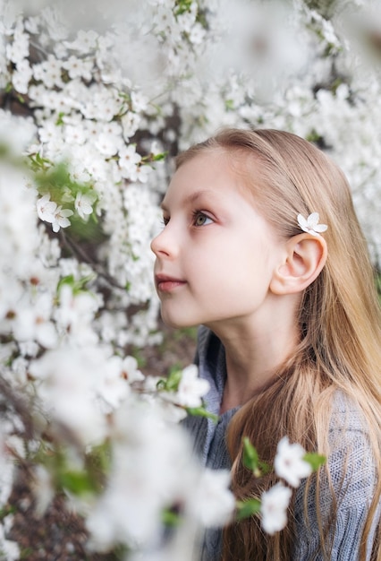 Nettes kleines Mädchen in einem blühenden Frühlingsgarten