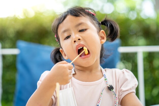 Nettes kleines Mädchen isst gerne Pommes zum Mittagessen im Freien