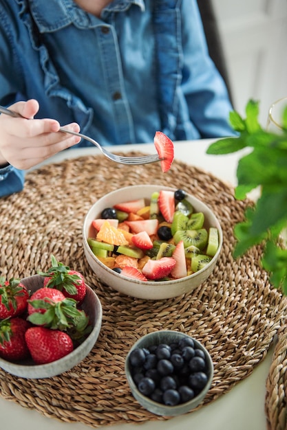 Nettes kleines Mädchen isst Obstsalat