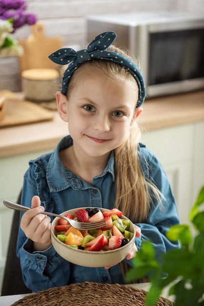 Nettes kleines Mädchen isst Obstsalat