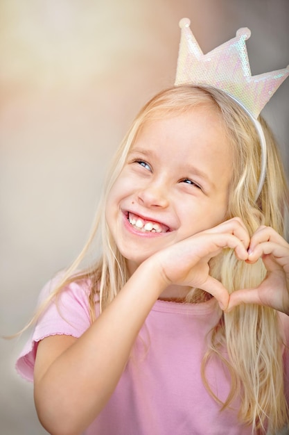 Nettes kleines Mädchen mit blonden Haaren mit einem weißen Herzen in ihren Händen