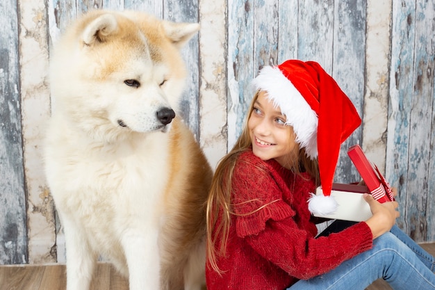 Nettes kleines Mädchen mit einem Hund mit Weihnachtsmützen