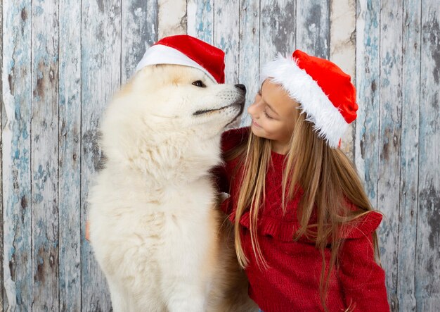 Nettes kleines Mädchen mit einem Hund mit Weihnachtsmützen