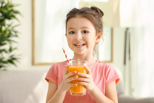 Nettes kleines Mädchen mit Glas Saft zu Hause