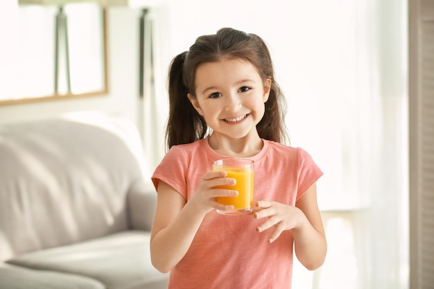 Nettes kleines Mädchen mit Glas Saft zu Hause