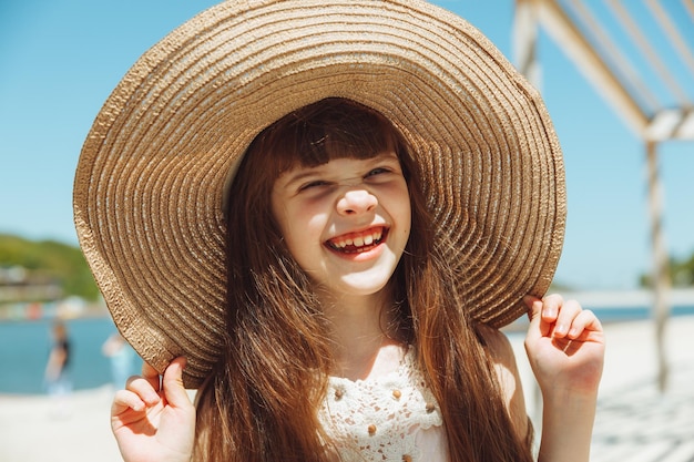 Nettes kleines Mädchen mit Hut lächelt an einem Sommertag am Strand Porträt eines Mädchens am Strand