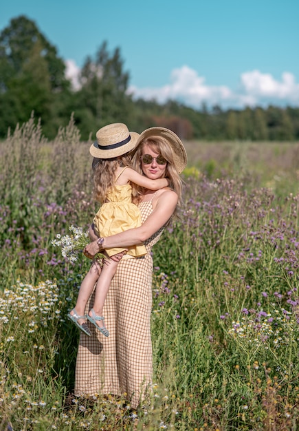 Nettes kleines mädchen mit ihrer mutter, die auf dem blumengebiet geht