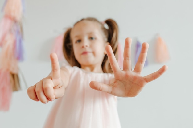 Nettes kleines Mädchen mit Partydekoration Kind zeigt sechs Jahre alte Quastenpapiergirlande