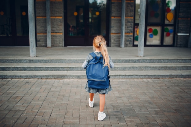 Nettes kleines Mädchen mit Rucksack, das zurück zur Schule geht