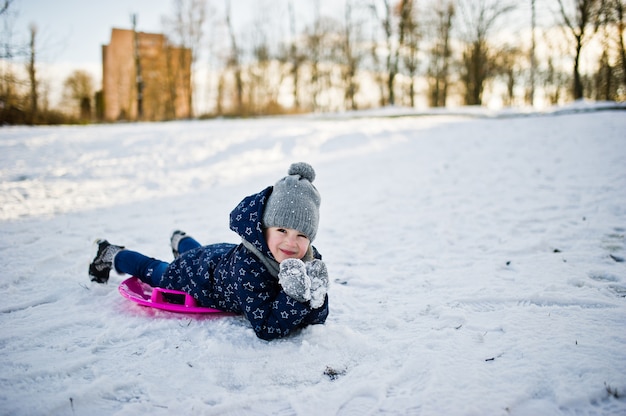 Nettes kleines Mädchen mit Untertassenschlitten draußen am Wintertag.