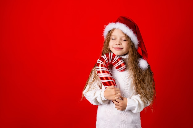 Nettes kleines Mädchen mit Weihnachtsmannmütze und einem Pullover