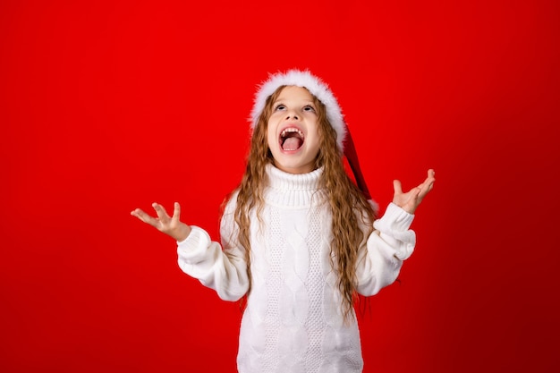 Nettes kleines Mädchen mit Weihnachtsmannmütze und einem Pullover