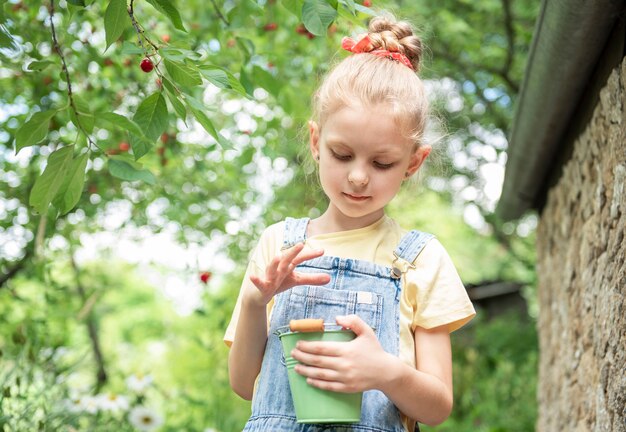 Nettes kleines Mädchen pflückt eine Kirsche von einem Baum im Kirschgarten