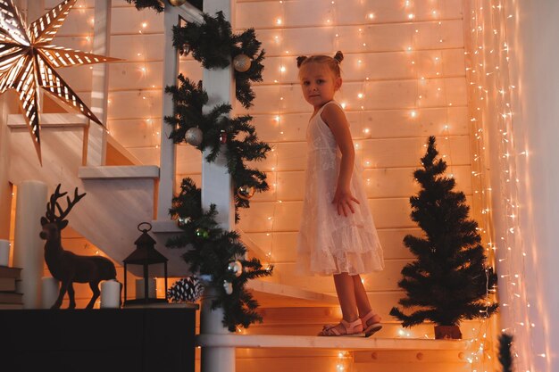 Nettes kleines Mädchen schmückt einen Weihnachtsbaum. Frohe Weihnachten und Neujahrsfeiertage.