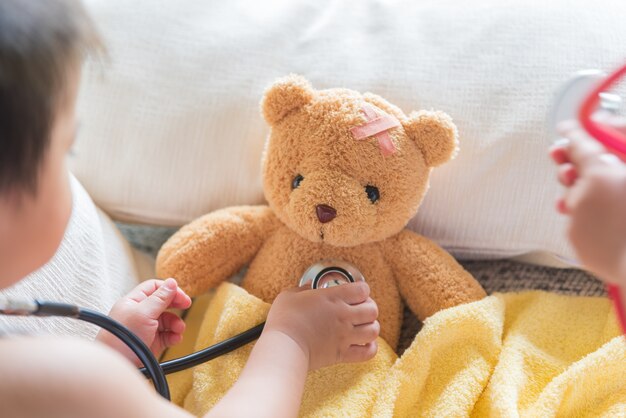 Nettes kleines Mädchen spielt Doktor mit Stethoskop und Teddybären.