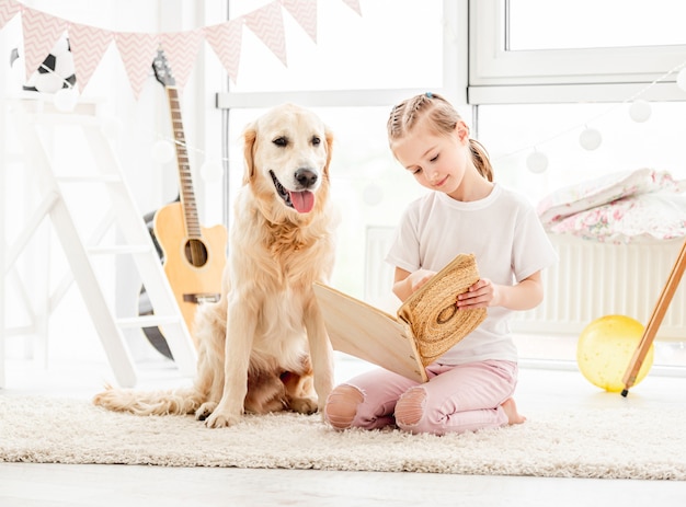 Nettes kleines Mädchen und Hund lesen