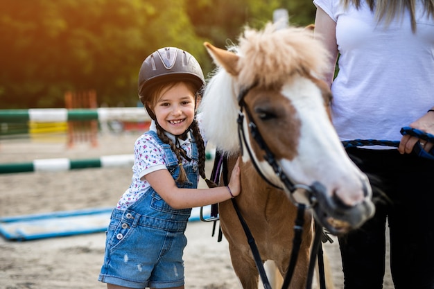 Nettes kleines Mädchen und ihre ältere Schwester, die draußen auf der Ranch mit Ponypferd genießen.