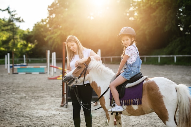 Nettes kleines Mädchen und ihre ältere Schwester, die draußen auf der Ranch mit Ponypferd genießen