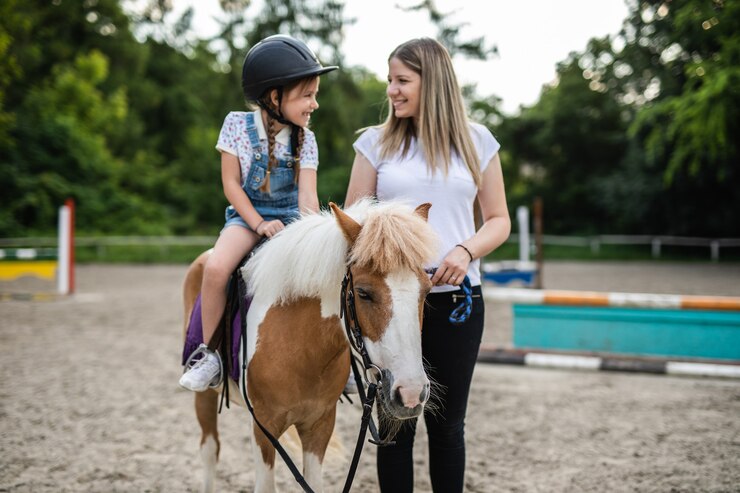 Nettes kleines Mädchen und ihre ältere Schwester, die draußen auf der Ranch mit Ponypferd genießen