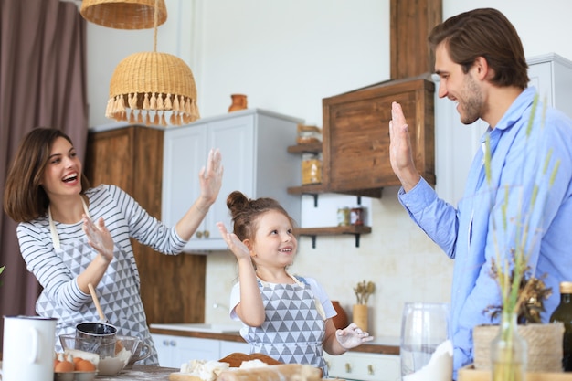 Nettes kleines Mädchen und ihre Eltern haben Spaß beim Kochen in der Küche zu Hause zusammen.