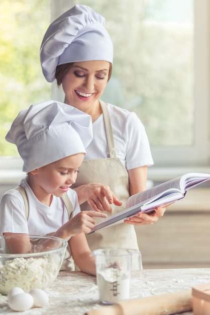 Nettes kleines Mädchen und ihre schöne Mutter lesen Rezept.