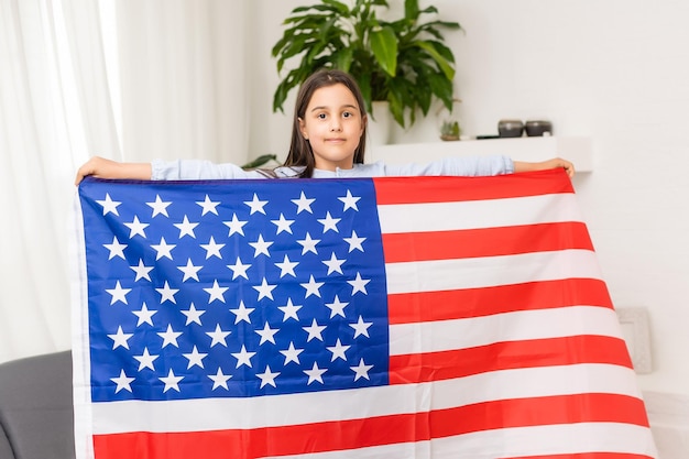 Nettes kleines Mädchen und USA-Flagge im Hintergrund.