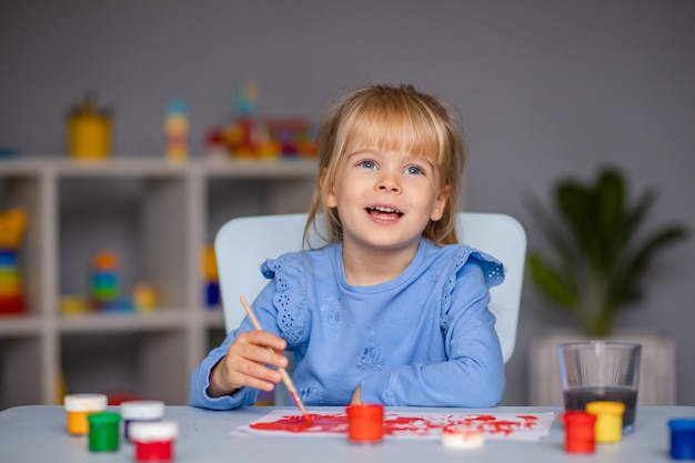 Nettes kleines Mädchen zeichnet mit Farben im Kindergarten