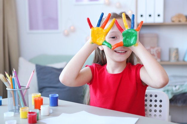 Nettes kleines Mädchen zeichnet zu Hause Farben